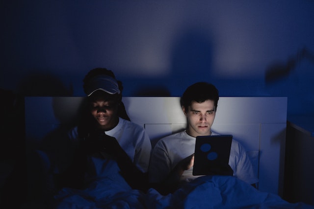 Sleep: Couple looking at devices in bed